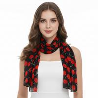 A woman modeling a lightweight black scarf with a vibrant red cherry print, styled around her neck over a white top against a plain white background.