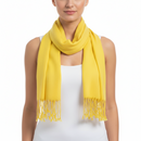 A woman wearing a bright yellow scarf with fringe ends, styled around her neck over a white sleeveless top against a plain white background.