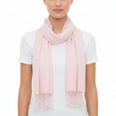 A model wearing a soft, light pink scarf with fringed ends over a white t-shirt, shot against a plain white background.