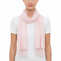 A model wearing a soft, light pink scarf with fringed ends over a white t-shirt, shot against a plain white background.