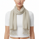 A woman wearing a light beige scarf with fringed tassels, styled over a white short-sleeve crop top against a plain white background.