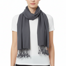 A model wearing a dark gray scarf with fringed tassels, styled over a white t-shirt against a plain white background.
