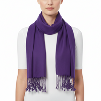 A model wearing a solid purple knit scarf with fringe tassels, styled around the neck over a white t-shirt against a plain white background.