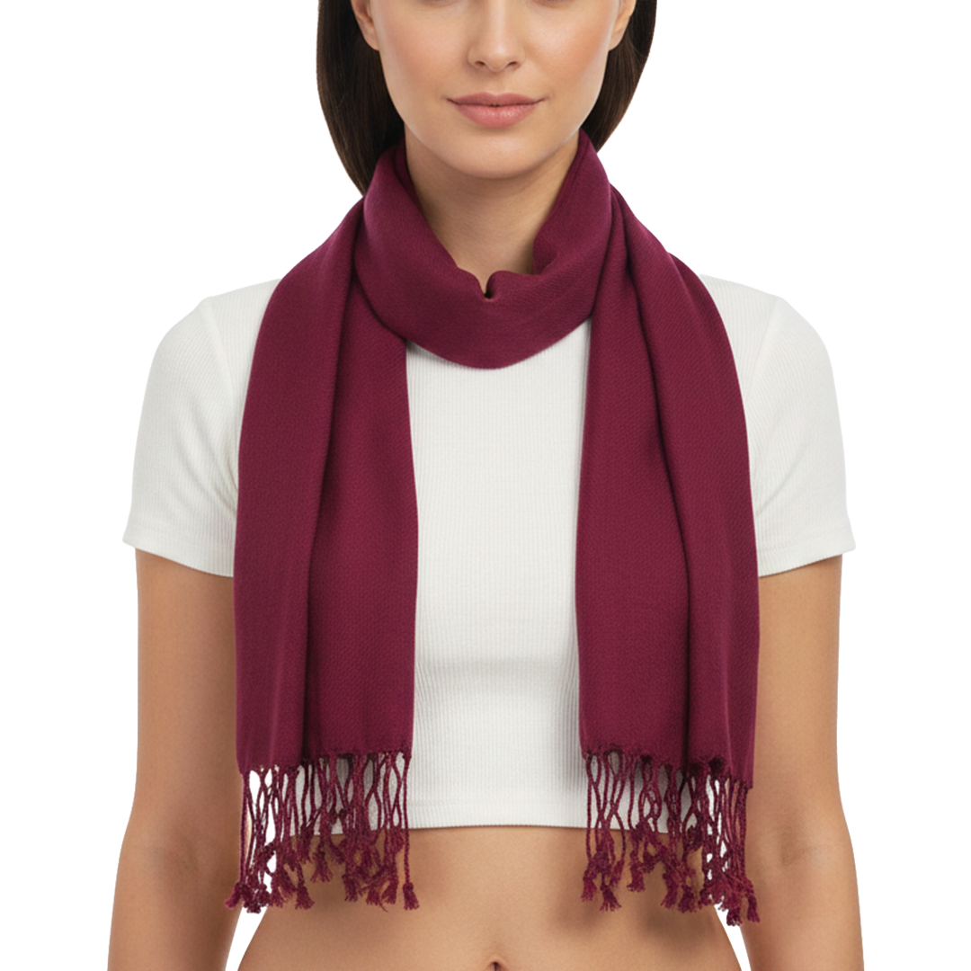 A woman modeling a deep burgundy scarf with fringed ends, worn around her neck over a white crop top against a plain white background.