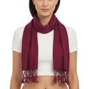 A woman modeling a deep burgundy scarf with fringed ends, worn around her neck over a white crop top against a plain white background.