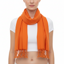 A bright orange scarf with fringed ends, wrapped around the neck of a model wearing a white crop top against a plain white background.