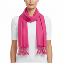 A bright pink scarf with fringed ends, worn in a loop around the neck of a model wearing a white t-shirt, against a plain white background.