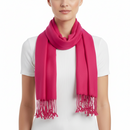 A bright pink scarf with fringed ends, worn in a loop around the neck of a model wearing a white ribbed short-sleeve top, against a plain white background.