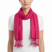 A bright pink scarf with fringed ends, worn in a loop around the neck of a model wearing a white ribbed short-sleeve top, against a plain white background.