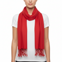 A bright red scarf with fringed ends, worn around the neck of a model wearing a white t-shirt against a plain white background.
