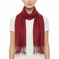 A model wearing a deep red scarf with fringed ends, styled over a white short-sleeve top against a plain white background.
