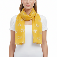 A woman wearing a bright yellow scarf with a repeating metallic gold elephant pattern, styled over a white t-shirt against a plain white background.