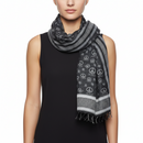 Person wearing a black and gray patterned scarf with peace signs on a white background