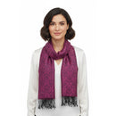 A woman with short dark hair wearing a white top and a magenta-purple patterned scarf with black fringe, photographed against a plain white background.