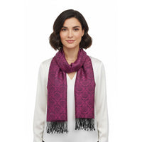 A woman with short dark hair wearing a white top and a magenta-purple patterned scarf with black fringe, photographed against a plain white background.