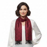A woman with short dark hair wearing a white blouse and a dark red patterned scarf with black fringe, photographed against a plain white background.