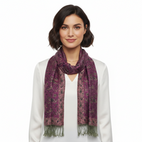 A woman with short dark hair wearing a white top and a purple patterned scarf with fringed ends, photographed against a plain white studio background.