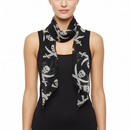 A model wearing a black scarf with a white skull and crossbones pirate print, styled around the neck over a black sleeveless top against a plain white background.