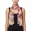A model wearing a lightweight pink scarf with a colorful butterfly and floral print, styled over a black sleeveless top against a plain white background.
