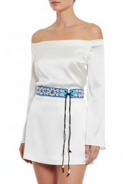 A blue and white beaded belt with adjustable strings, featuring a floral pattern and seashell designs.