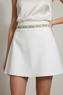 A beige belt with blue beads and seashells, featuring adjustable strings.