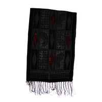 A black woven scarf with geometric and paisley patterns, featuring red accents and fringed edges, shown against a plain white background.