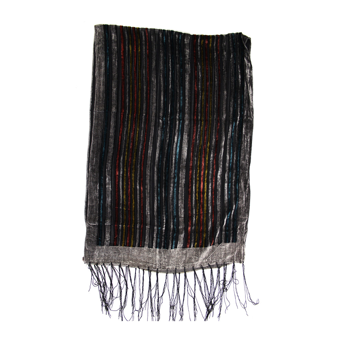A rectangular woven textile with vertical multicolor stripes in black, gray, red, and green, finished with a fringed hem, shown against a plain white background.