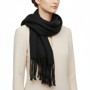 A black, solid-colored, fluffy thick winter scarf with fringed ends.